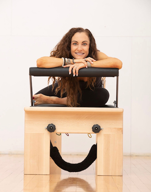 Picture of Bonnie Rich, Facial stretch therapist, Pilates trainer, and health coach on a reformer posing and smiling