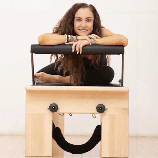 Picture of Bonnie Rich, Facial stretch therapist, Pilates trainer, and health coach on a reformer posing and smiling in a picture that is formatted in a square